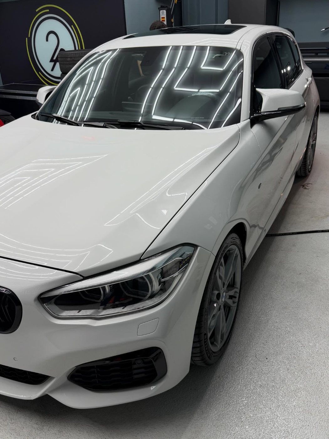 BMW 135i branca refletindo as luzes do teto